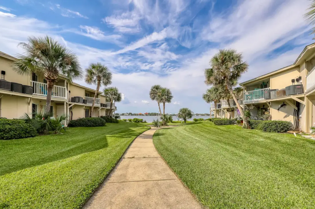A landscaped walkway runs between low-rise buildings toward the water.