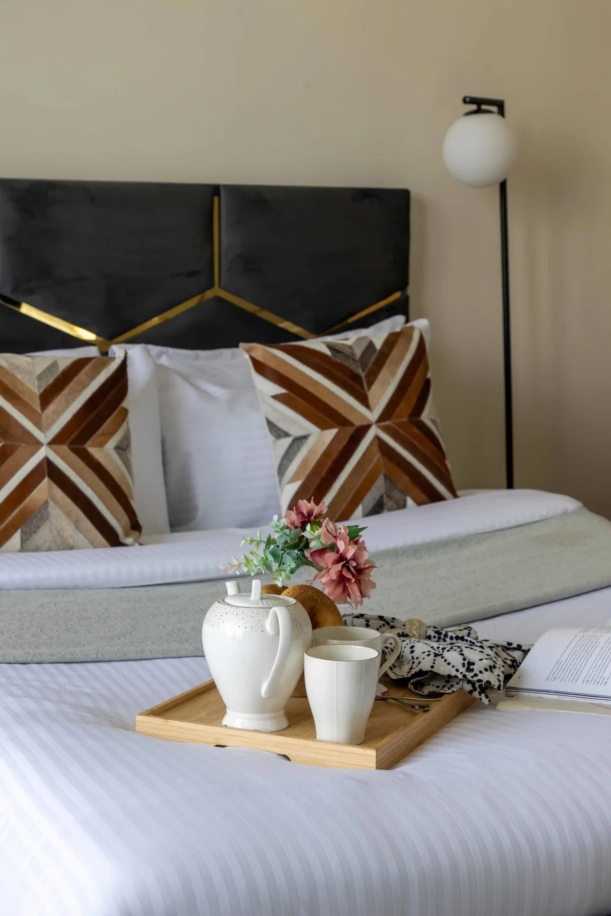 Un dormitorio con una cama tendida y cojines decorativos estampados.