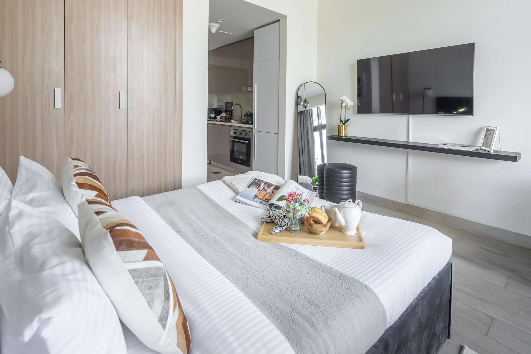 Un dormitorio con una cama bien tendida y un televisor montado en la pared.