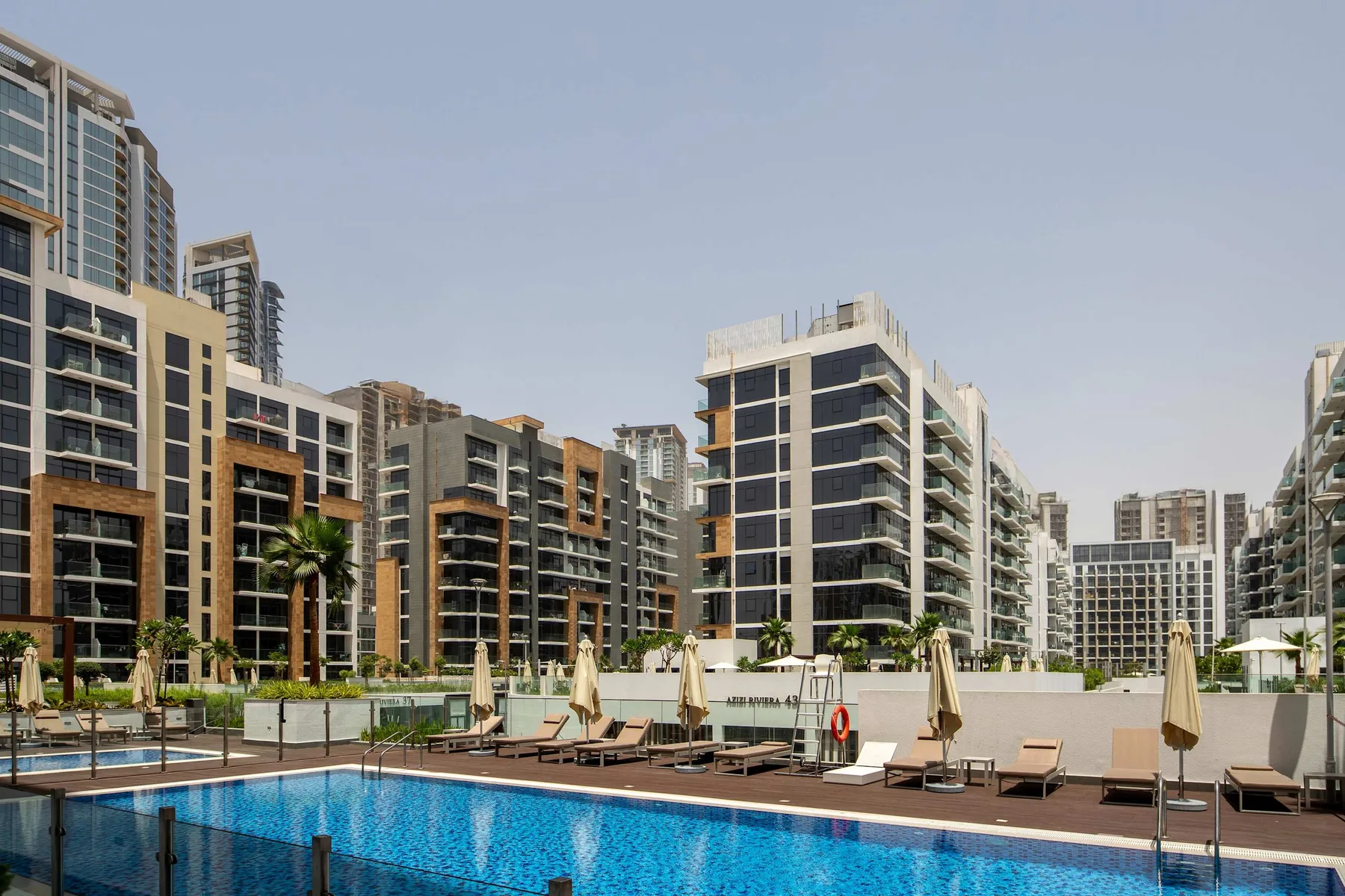Una piscina al aire libre está rodeada de edificios de apartamentos modernos.