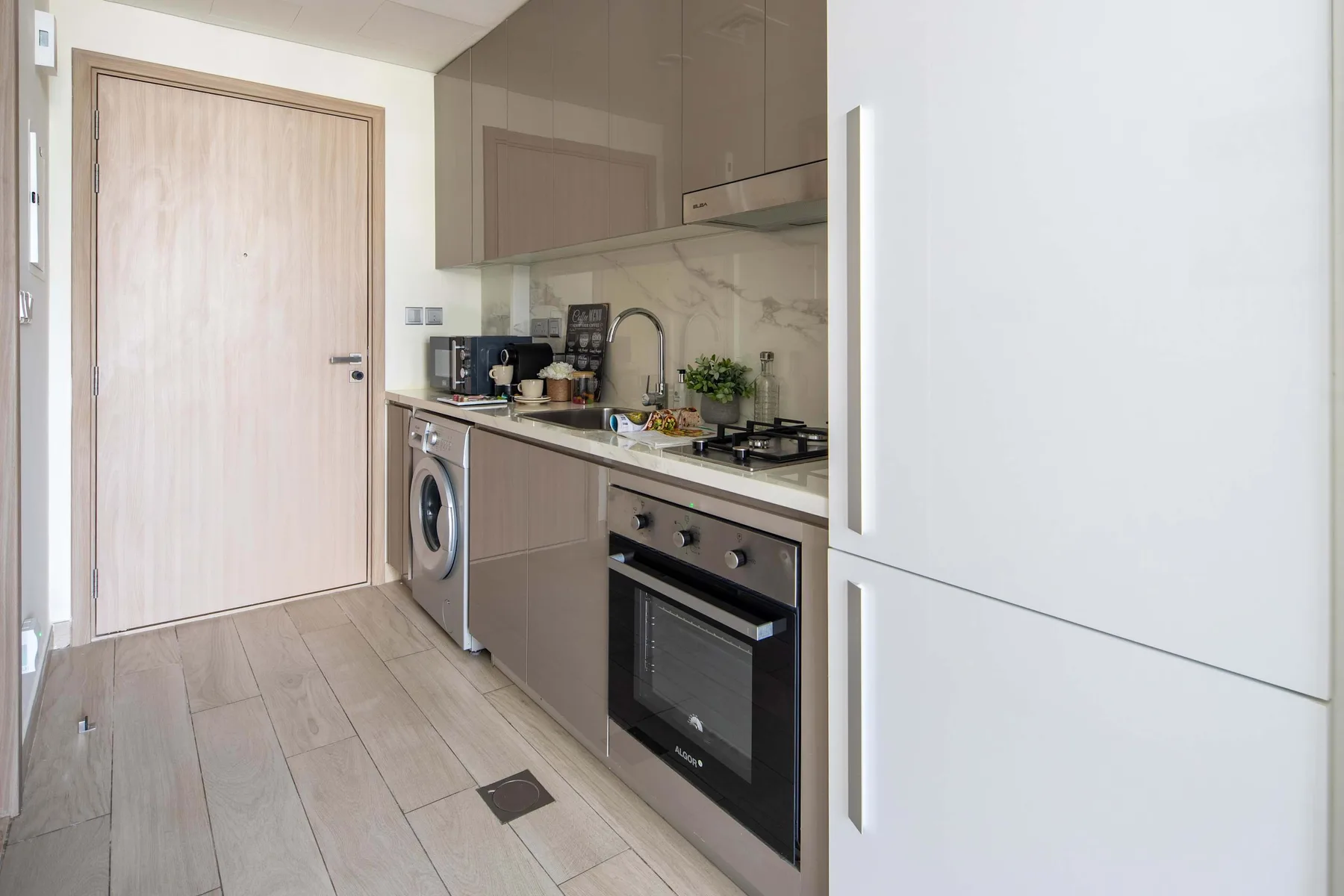 Una cocina compacta con encimera, placa de cocción, horno y refrigerador.