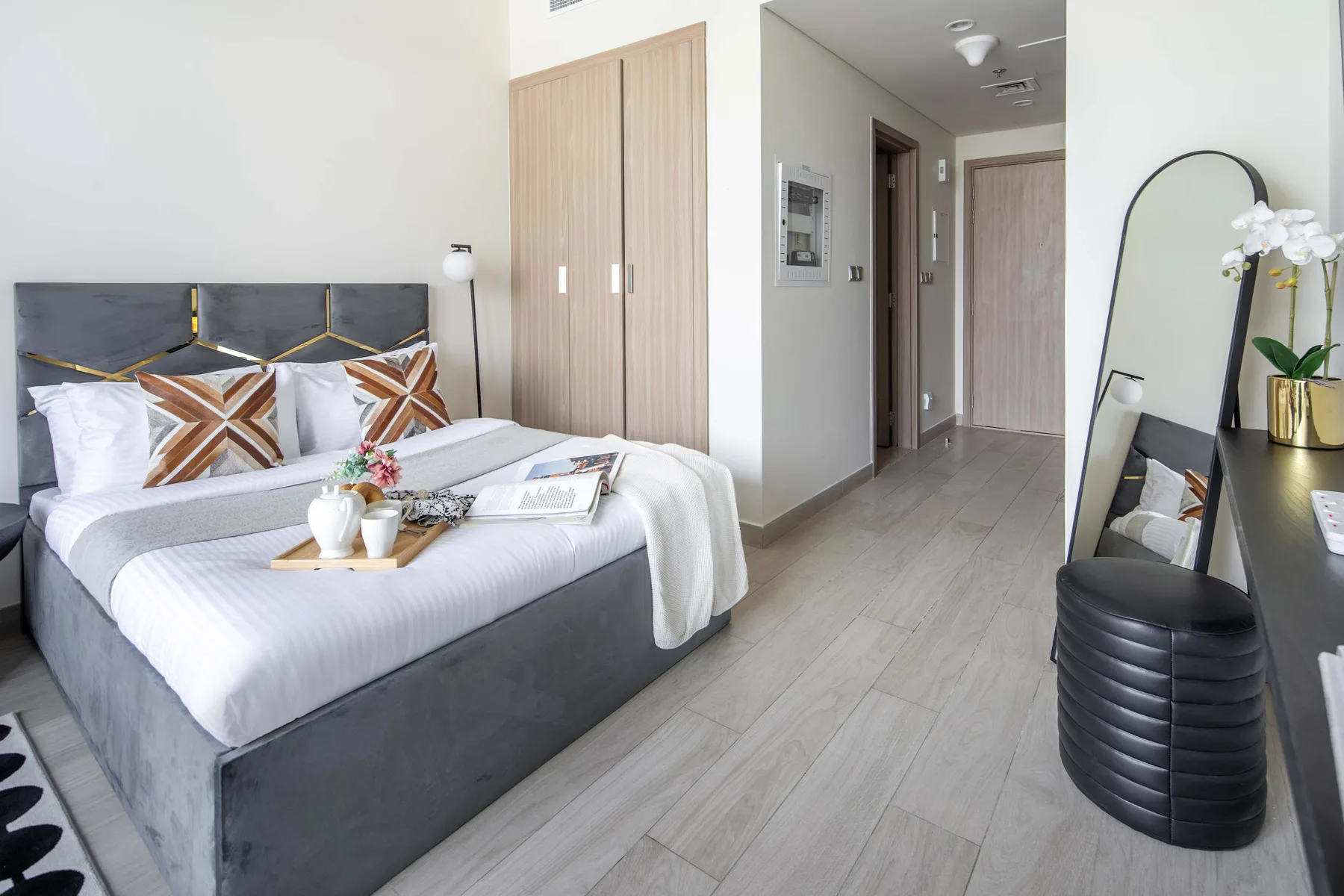 Un dormitorio con una cama bien hecha y un tocador junto al pasillo.