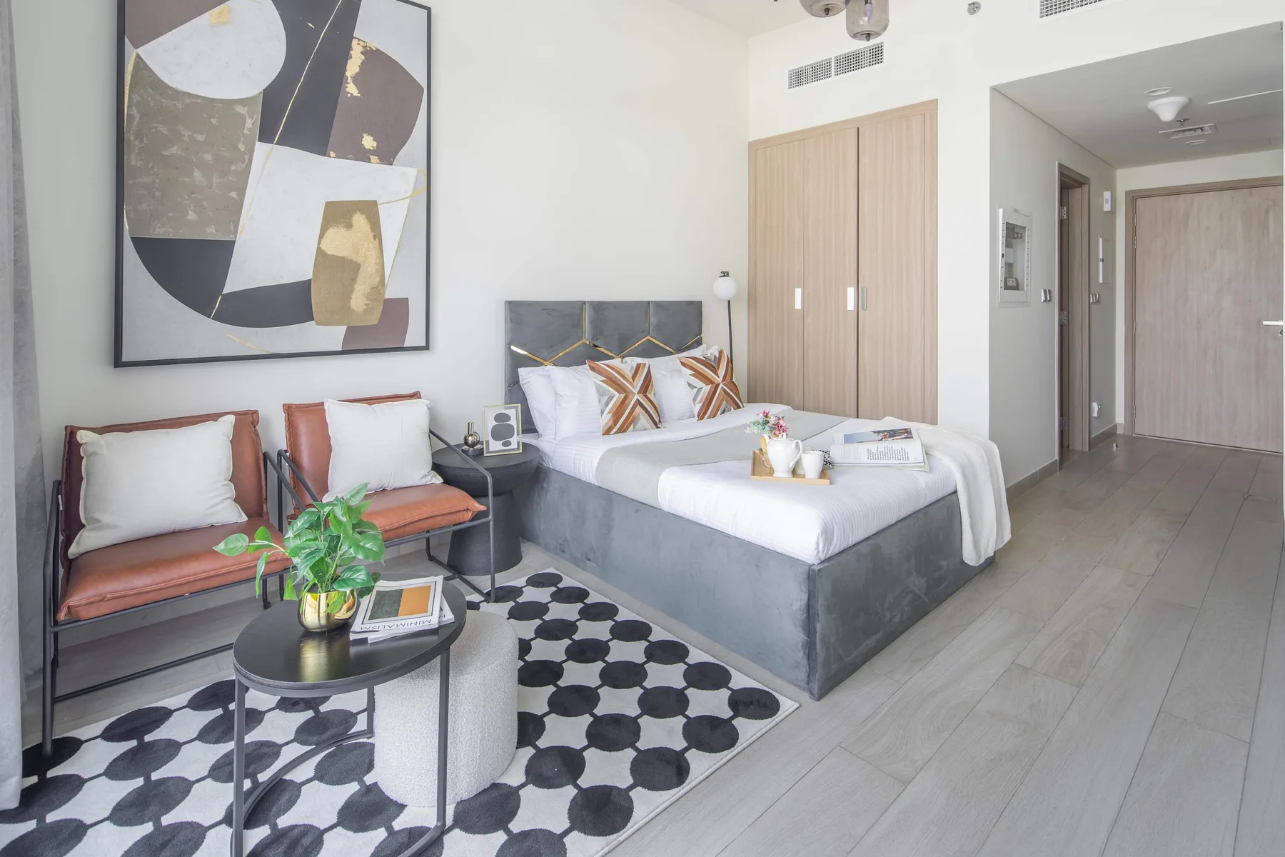 Un dormitorio luminoso con una cama grande, asientos y una alfombra estampada.