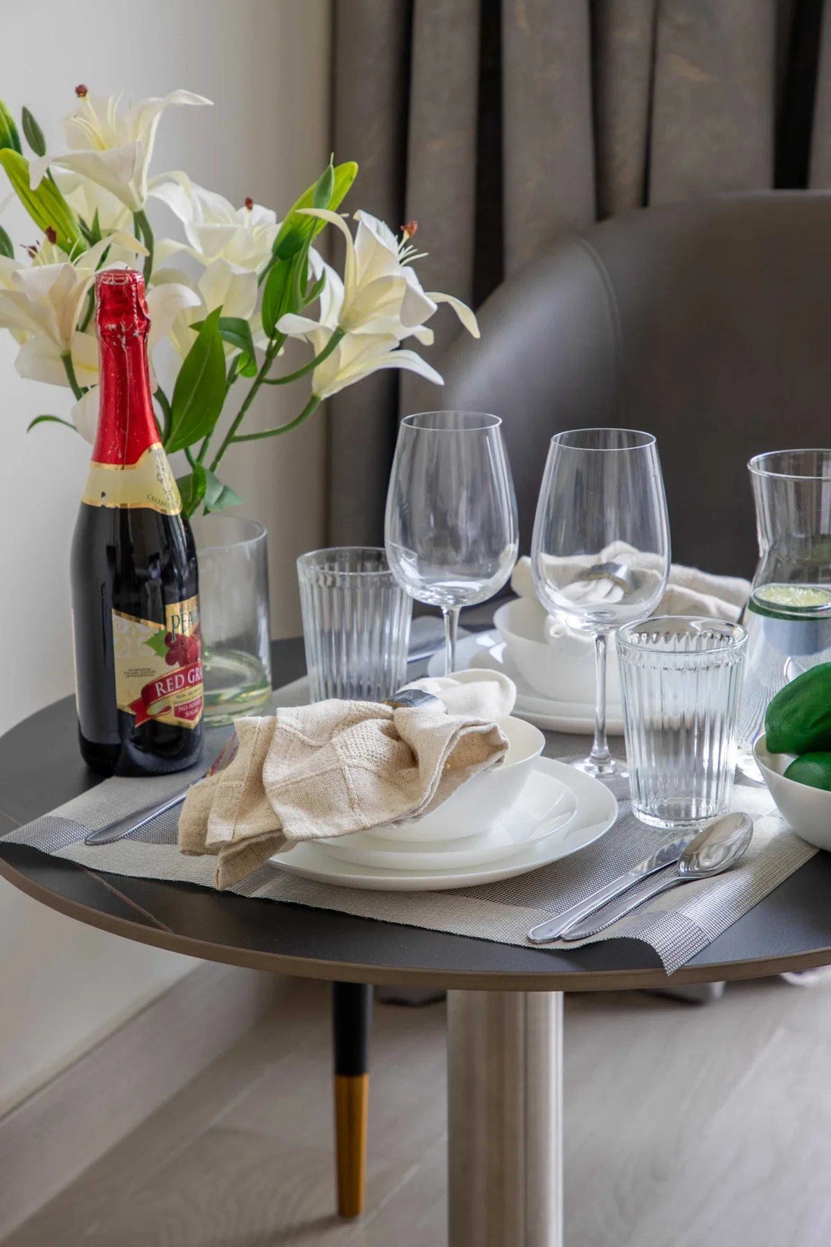 Una mesa está preparada con platos, copas, una botella y flores.