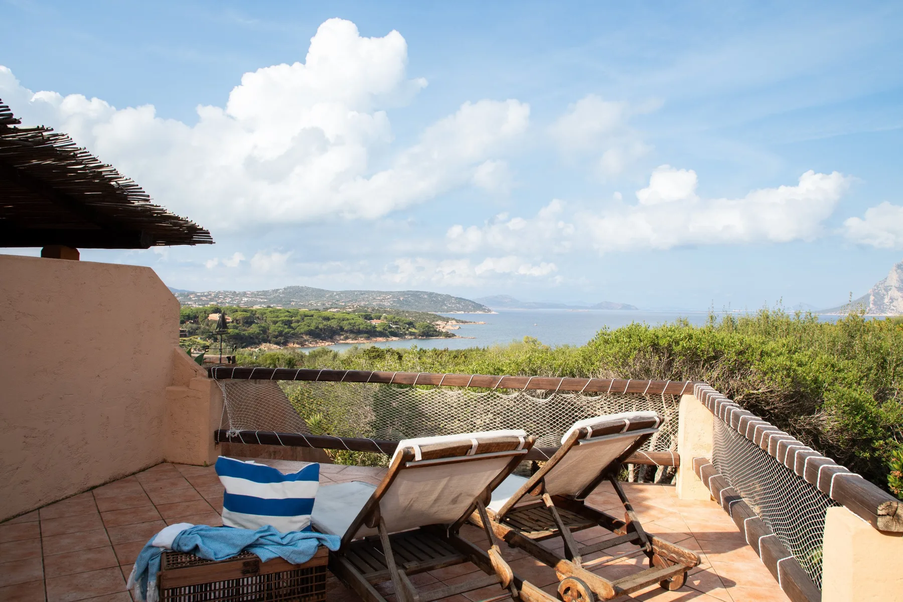 Una terraza con asientos reclinables ofrece vistas al mar y a un paisaje costero.