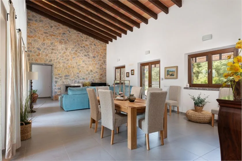 A dining area with a wooden table and seating beside a stone accent wall.