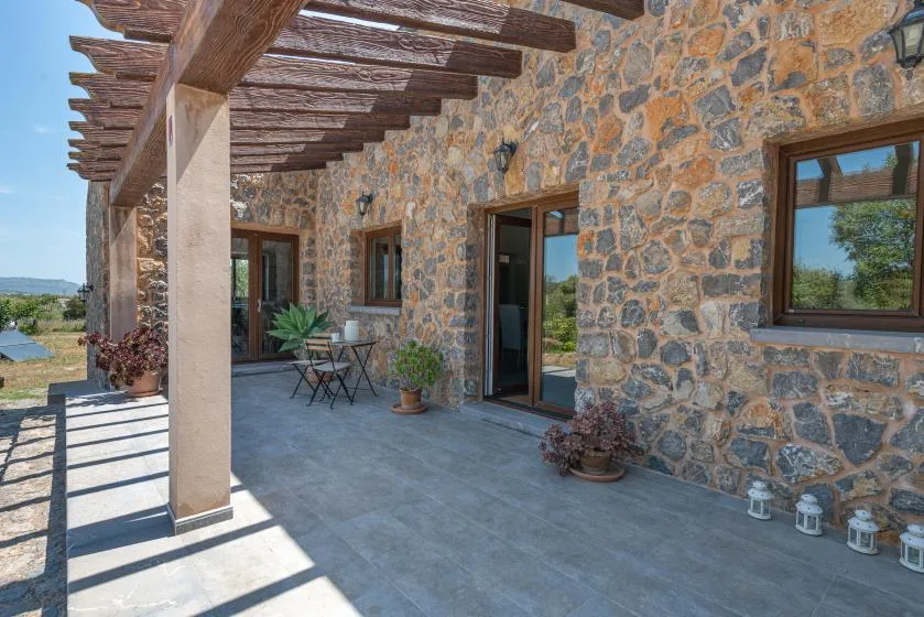 A stone-walled patio with a covered timber pergola and outdoor seating.