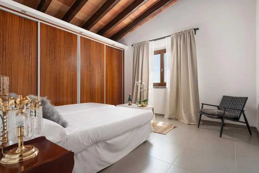 A bedroom with a bed, wood-paneled wardrobes, and a curtained window.
