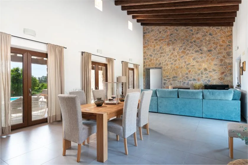 A dining area with a wooden table and seating beside a blue sofa.