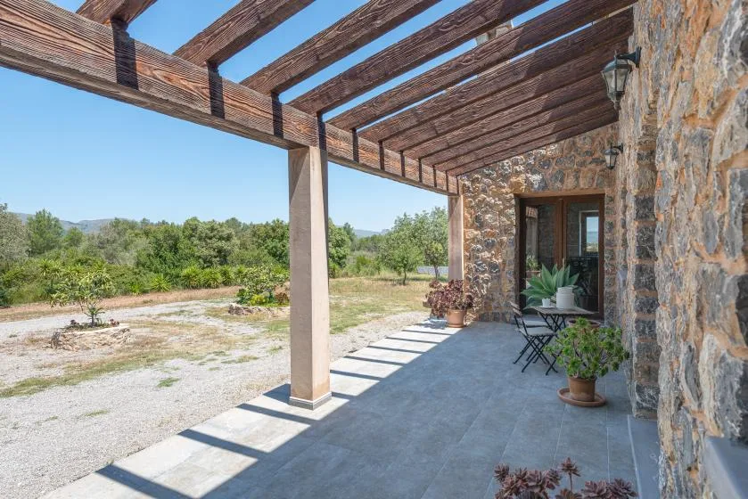 A covered outdoor patio with a wooden pergola overlooks a landscaped yard.