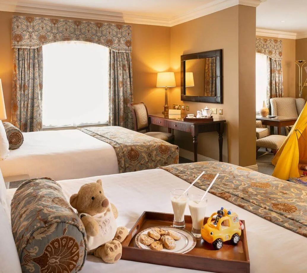 Habitación familiar de hotel con dos camas individuales, juguetes y una tienda de campaña de juegos.