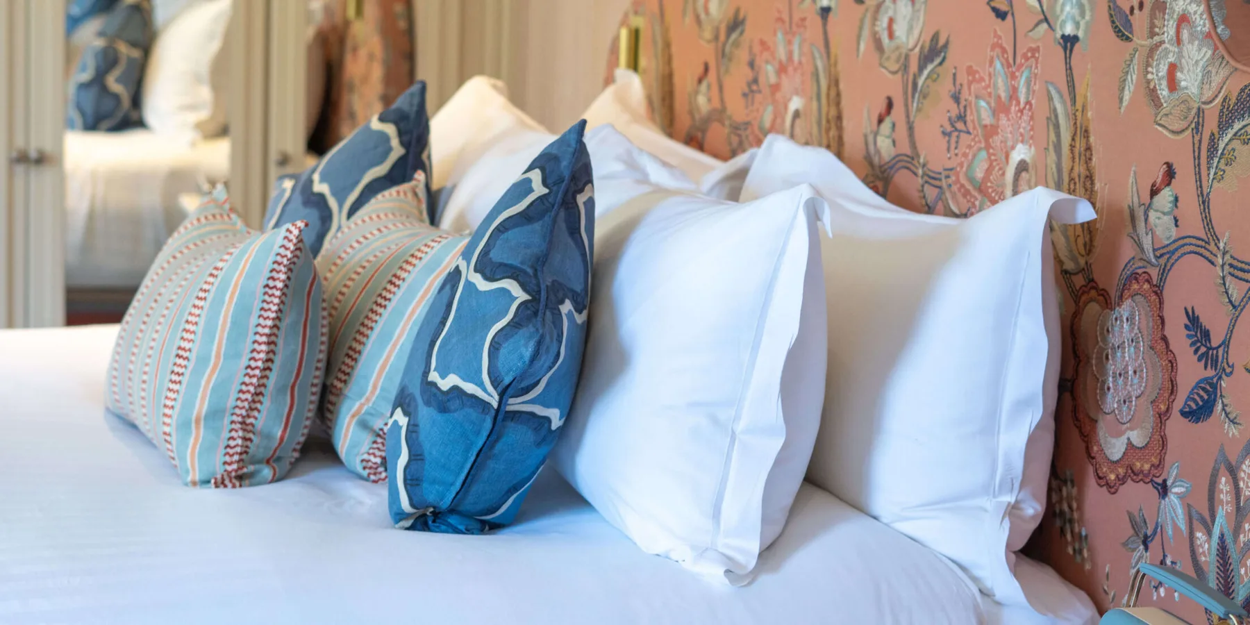Habitación de hotel con una cama y un cabecero con estampado floral.