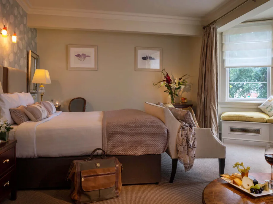 Habitación de hotel con una cama, decoración elegante y asientos junto a la ventana.