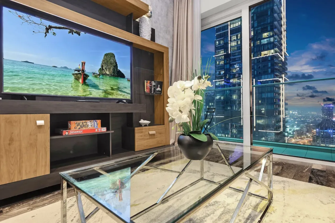 Una sala de estar moderna con una mesa de centro de vidrio y grandes ventanas con vistas a la ciudad.