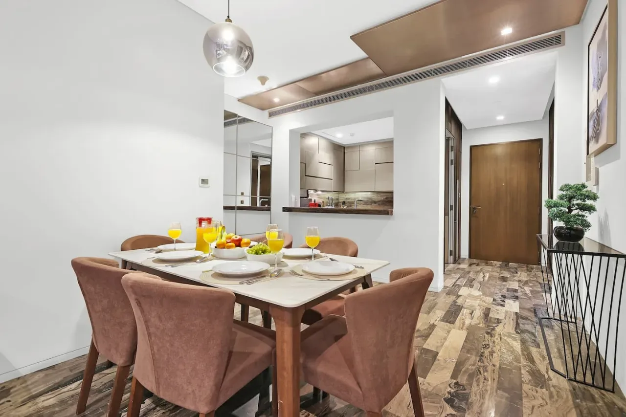 Comedor con una mesa puesta junto a una cocina abierta y un pasillo.