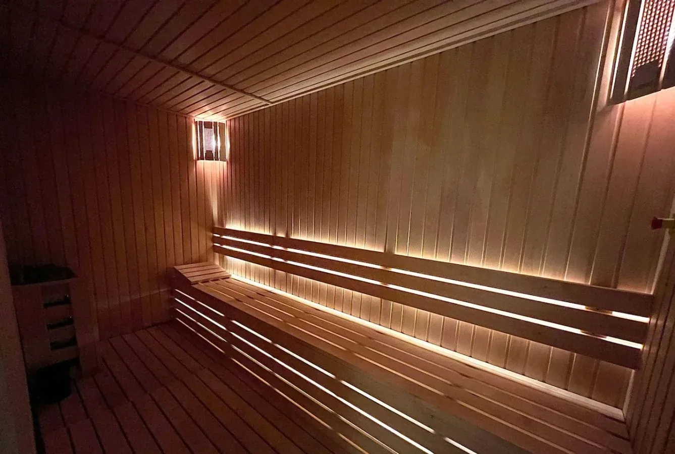 Una sauna revestida de madera con asientos escalonados e iluminación cálida.