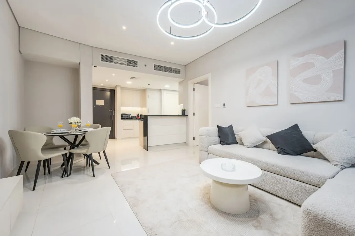 Una luminosa sala de estar y comedor de planta abierta con un sofá blanco y una mesa.