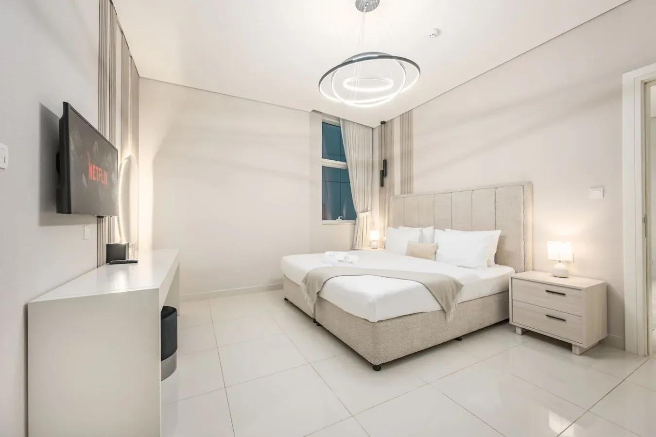 Un dormitorio luminoso con una cama grande y un televisor montado en la pared.