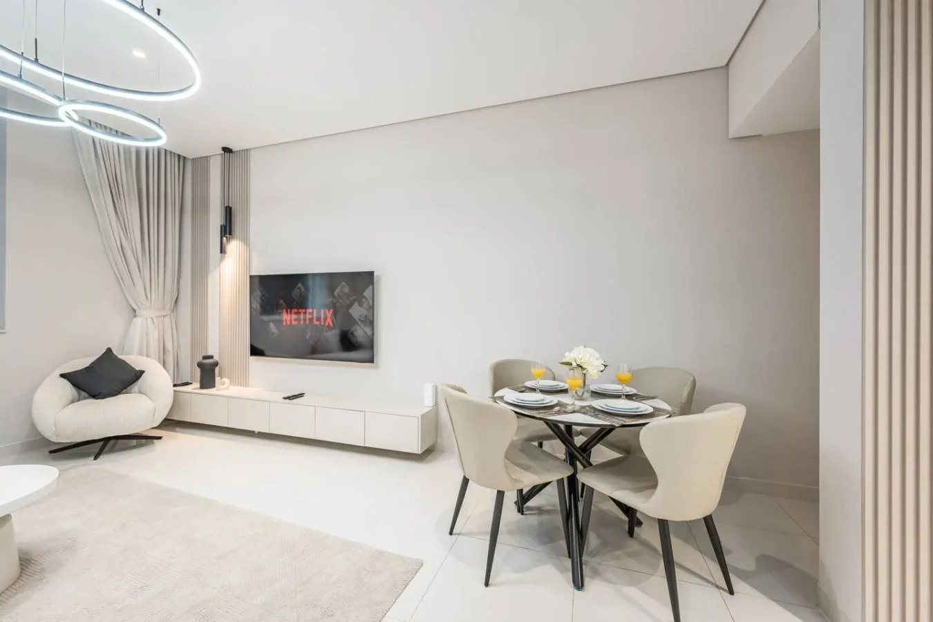 Una moderna sala de estar y comedor con televisor y mesa redonda.
