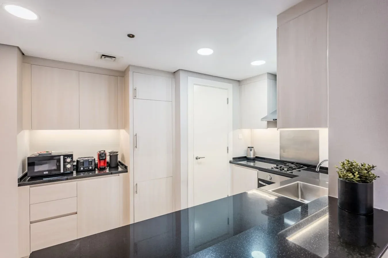 Una cocina moderna con gabinetes claros y encimeras oscuras.