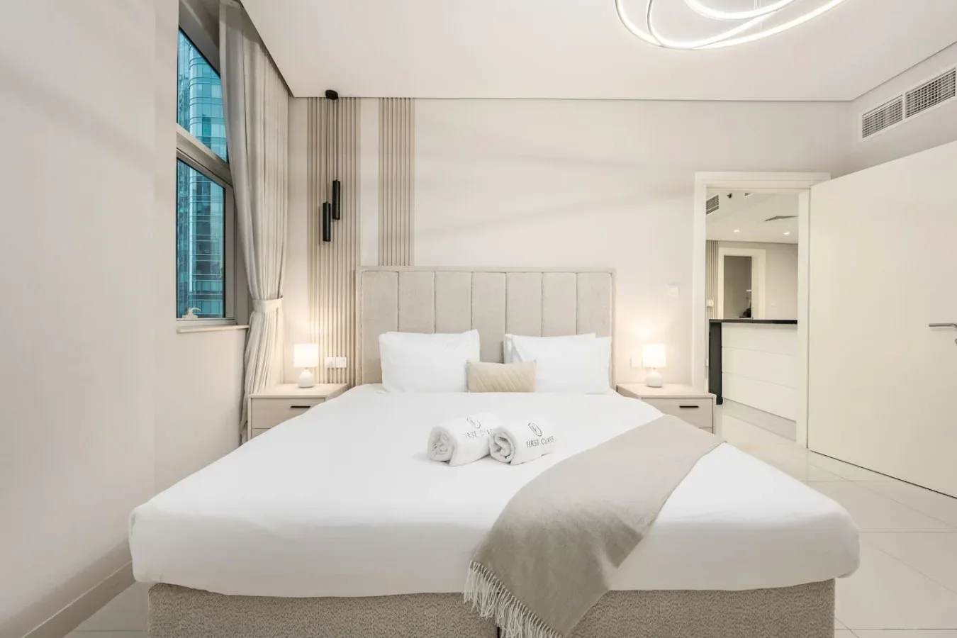Un dormitorio luminoso con una cama bien arreglada y una ventana grande.