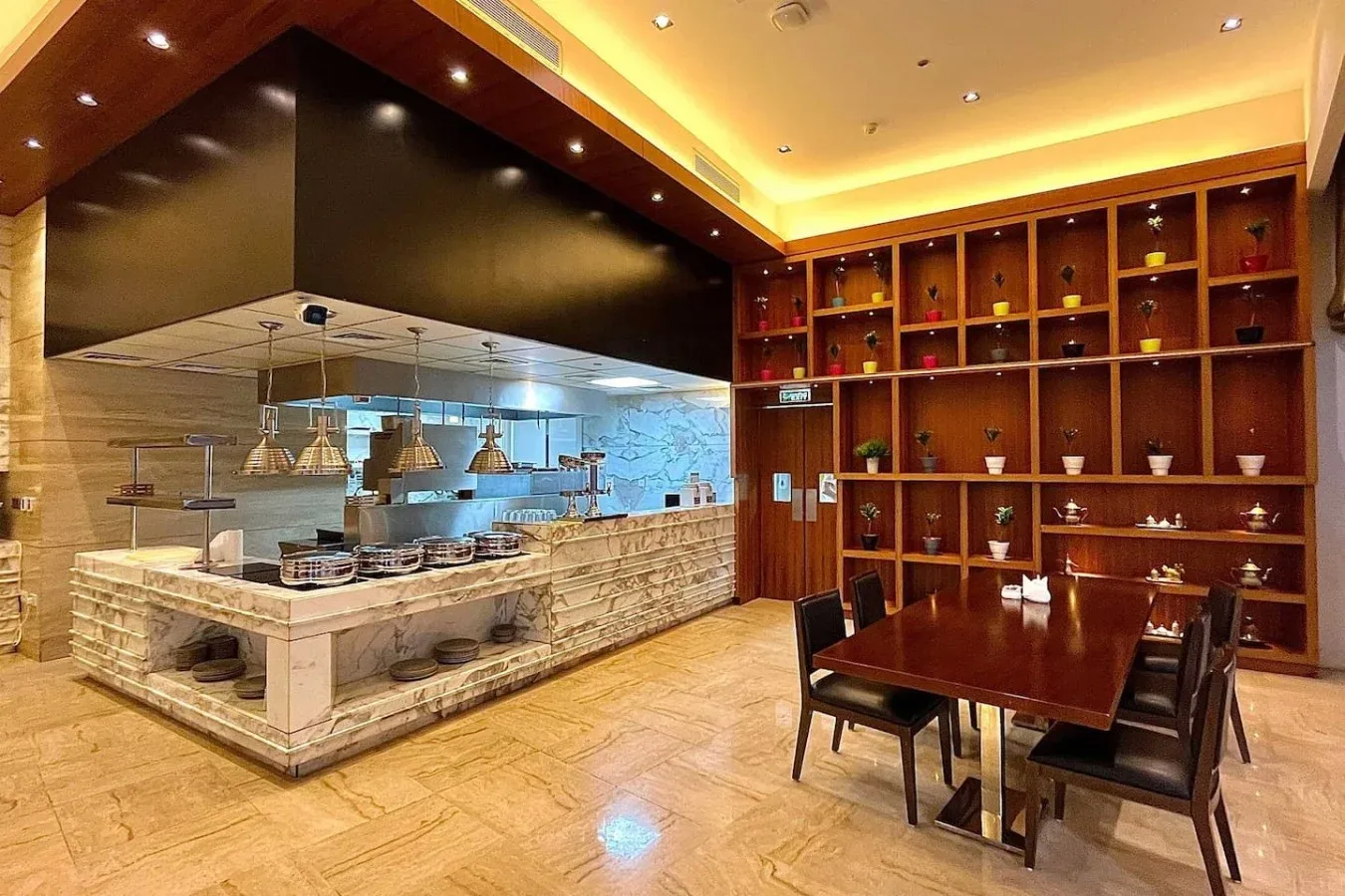 Un comedor de restaurante con una barra larga, luces colgantes y estanterías de madera.