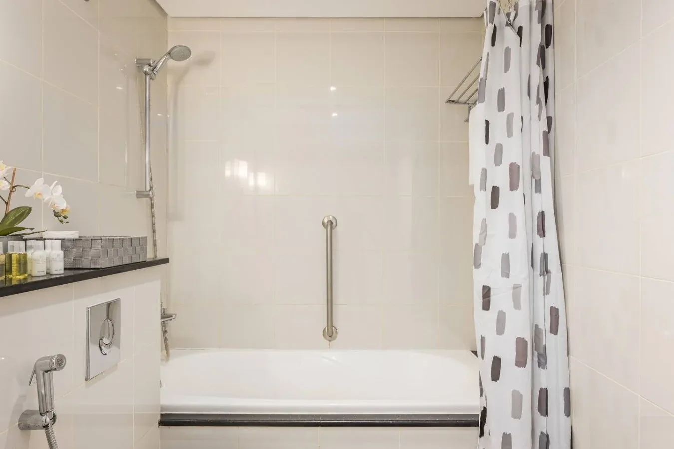 Un baño alicatado con bañera, ducha de pared y cortina estampada.
