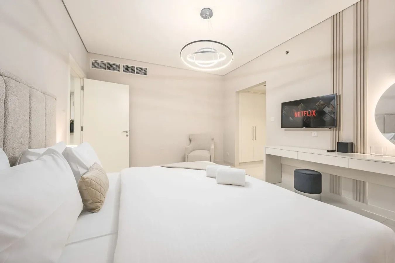 Un dormitorio luminoso con una cama grande y un televisor en la pared.