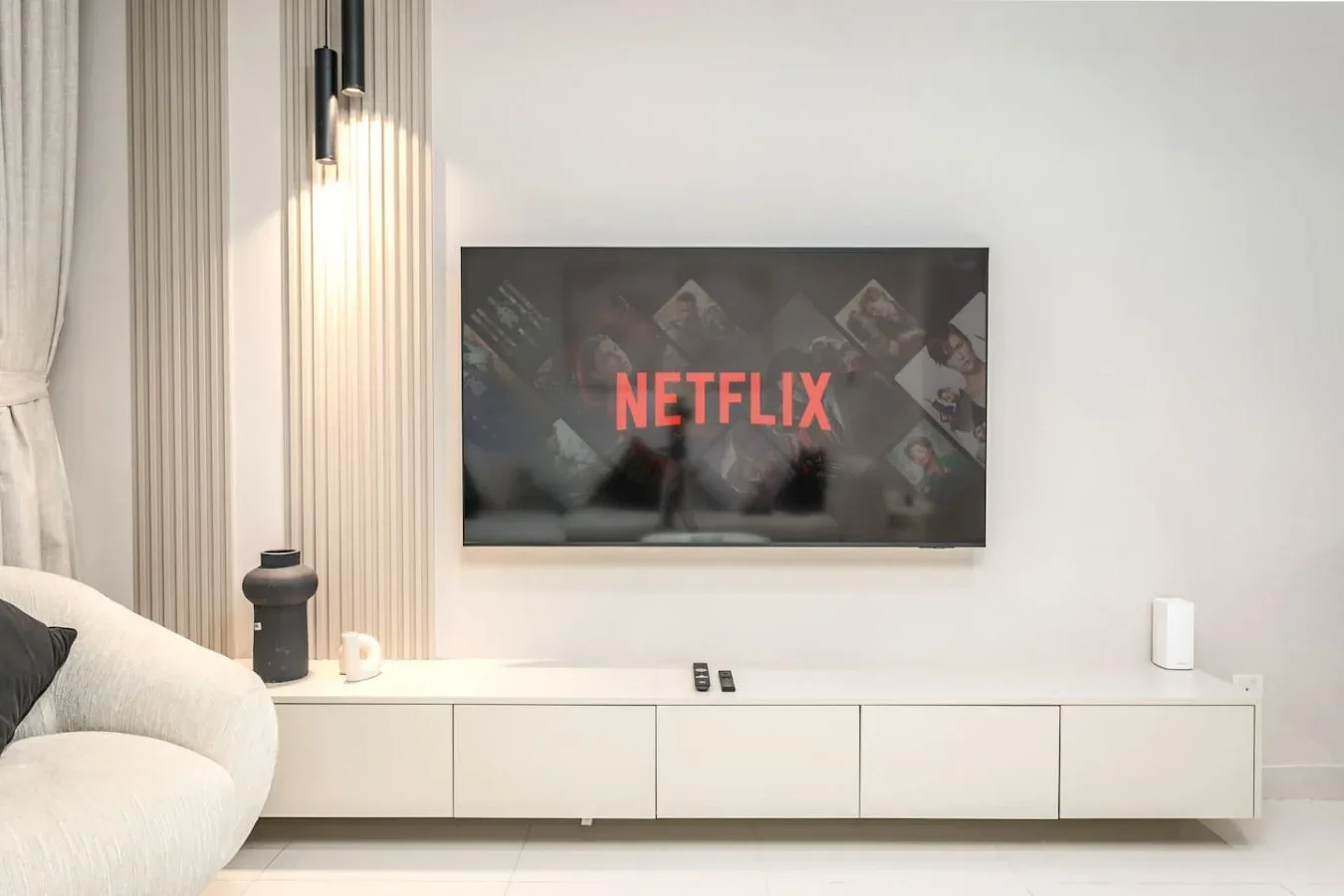 Una sala de estar con un televisor montado en la pared sobre un mueble bajo.