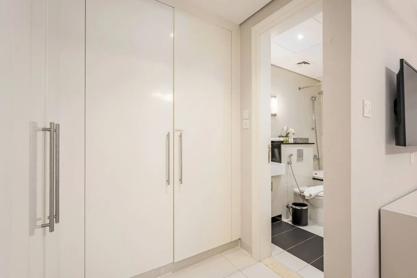 Un pasillo luminoso con armarios empotrados y una puerta abierta al baño.