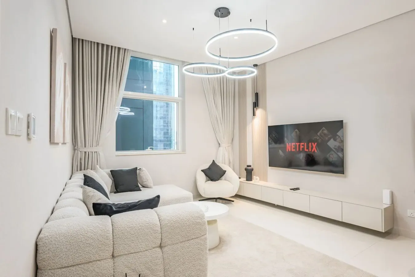 Una sala luminosa con asientos, una ventana grande y un televisor montado en la pared.