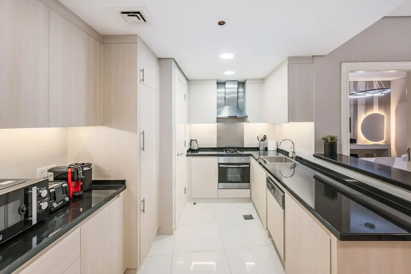 Una cocina moderna con gabinetes claros, encimeras oscuras y electrodomésticos empotrados.