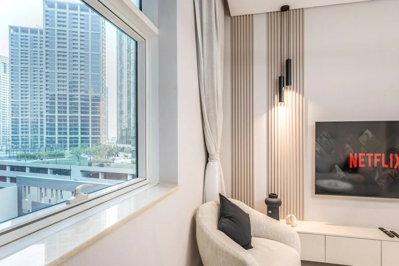 Una sala luminosa con una ventana grande, asientos y un televisor.