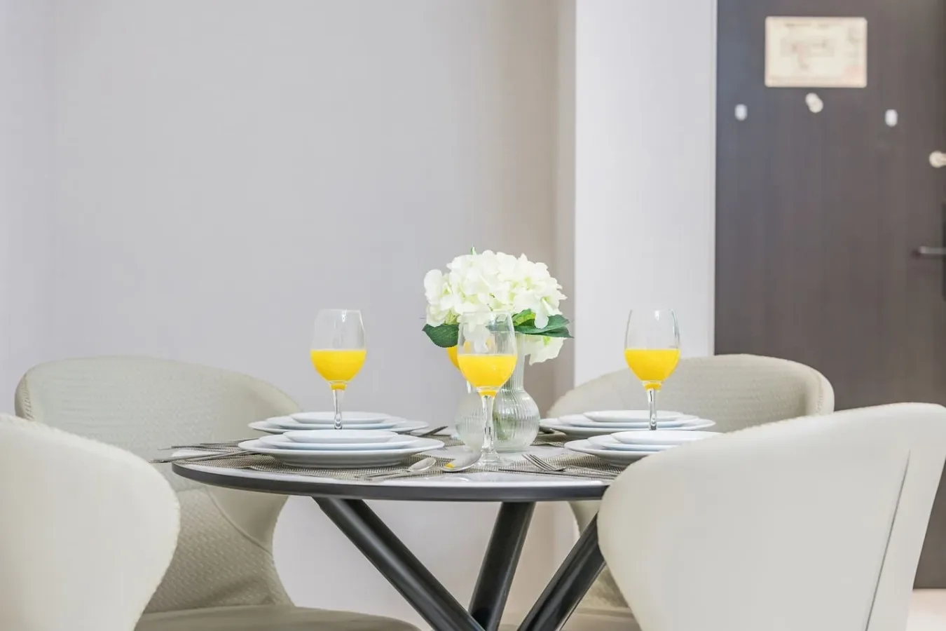 Una mesa de comedor está puesta con platos, copas y un jarrón de flores.