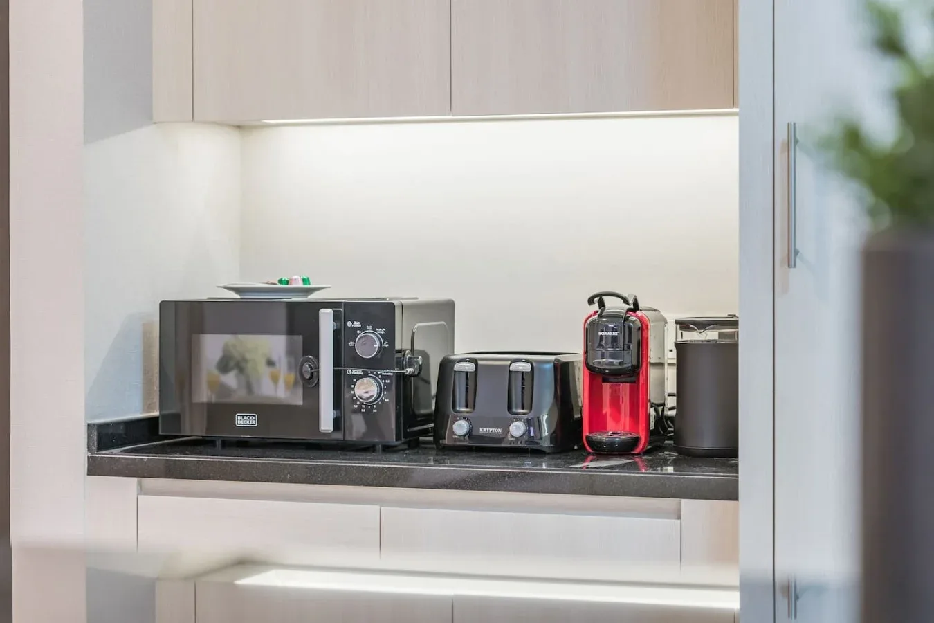 Una encimera de cocina con microondas, tostadora y cafetera.