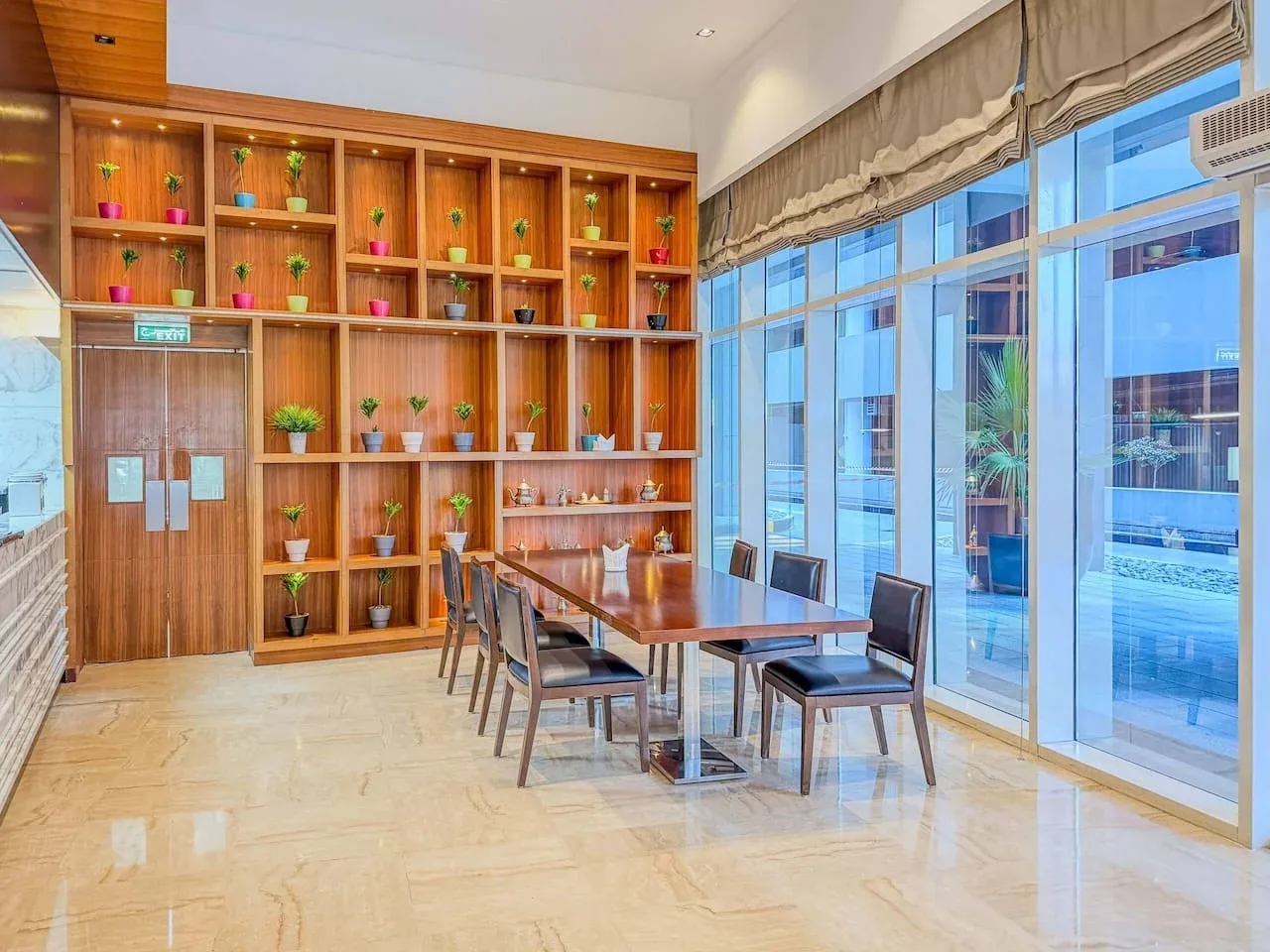 Un comedor con una mesa de madera y sillas junto a ventanales.