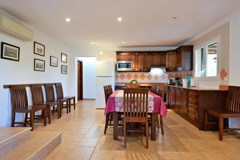 Un comedor con una mesa de madera junto a una cocina con gabinetes oscuros.