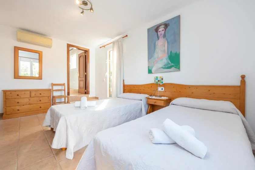 Un dormitorio luminoso con dos camas y una cómoda de madera.