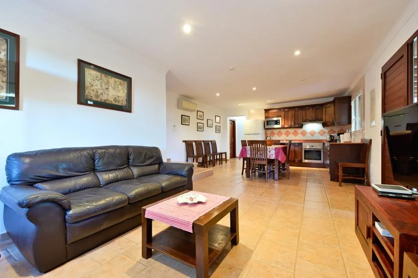 Una sala con comedor se abre a la cocina, con asientos y una mesa de centro.