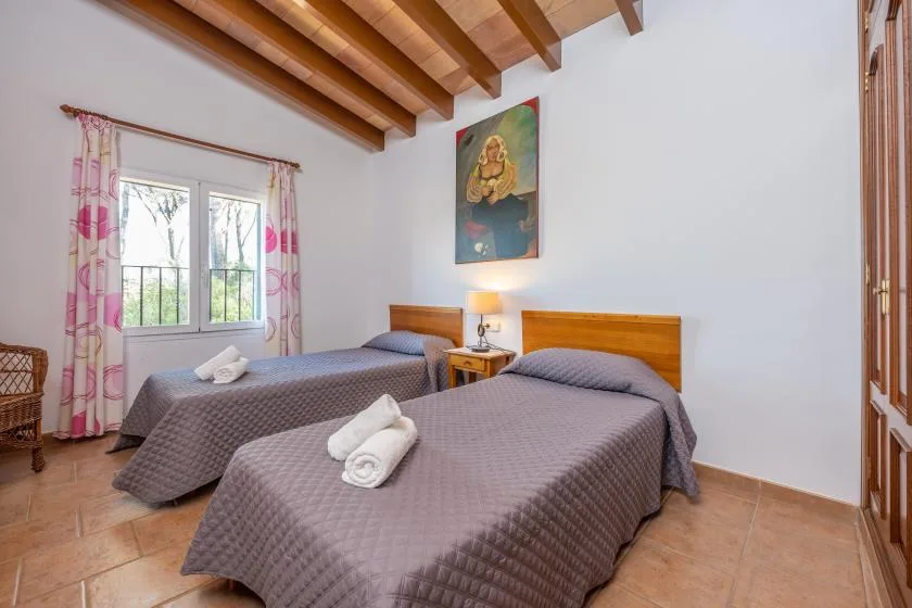 Un dormitorio con dos camas, una ventana y vigas de madera expuestas en el techo.