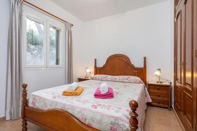 Un dormitorio con una cama de madera, ropa de cama floral y una ventana.