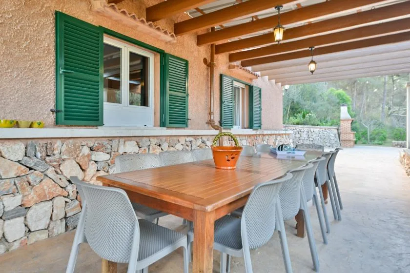 Comedor exterior cubierto con una mesa de madera y asientos grises.