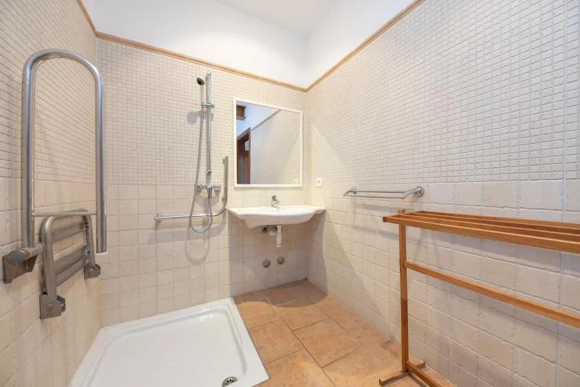 Un baño alicatado con ducha, lavabo y toallero de madera.