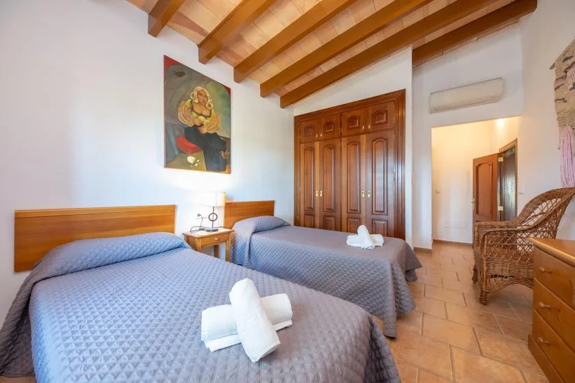 Un dormitorio con dos camas, armarios de madera y vigas de techo a la vista.