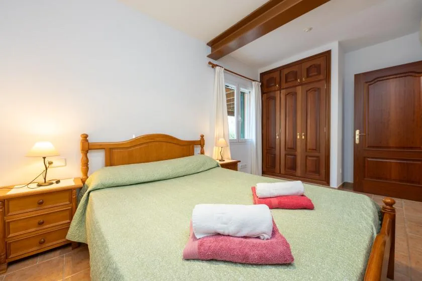 Un dormitorio con una cama de madera, mesillas de noche y un armario.