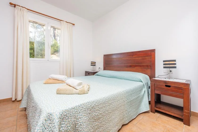 Un dormitorio luminoso con una cama junto a una ventana con cortinas.