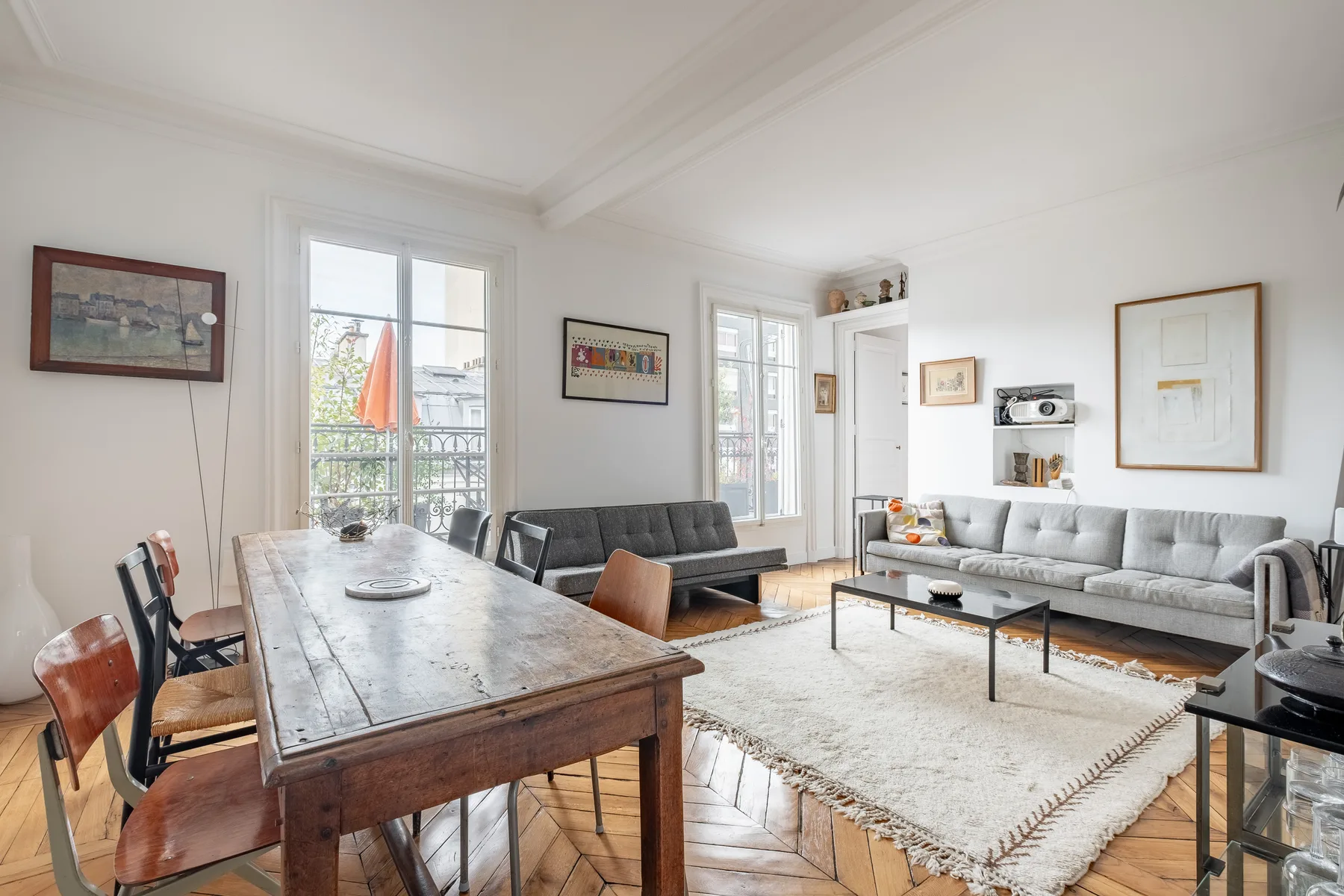 A bright living and dining room with a long wooden table and seating.