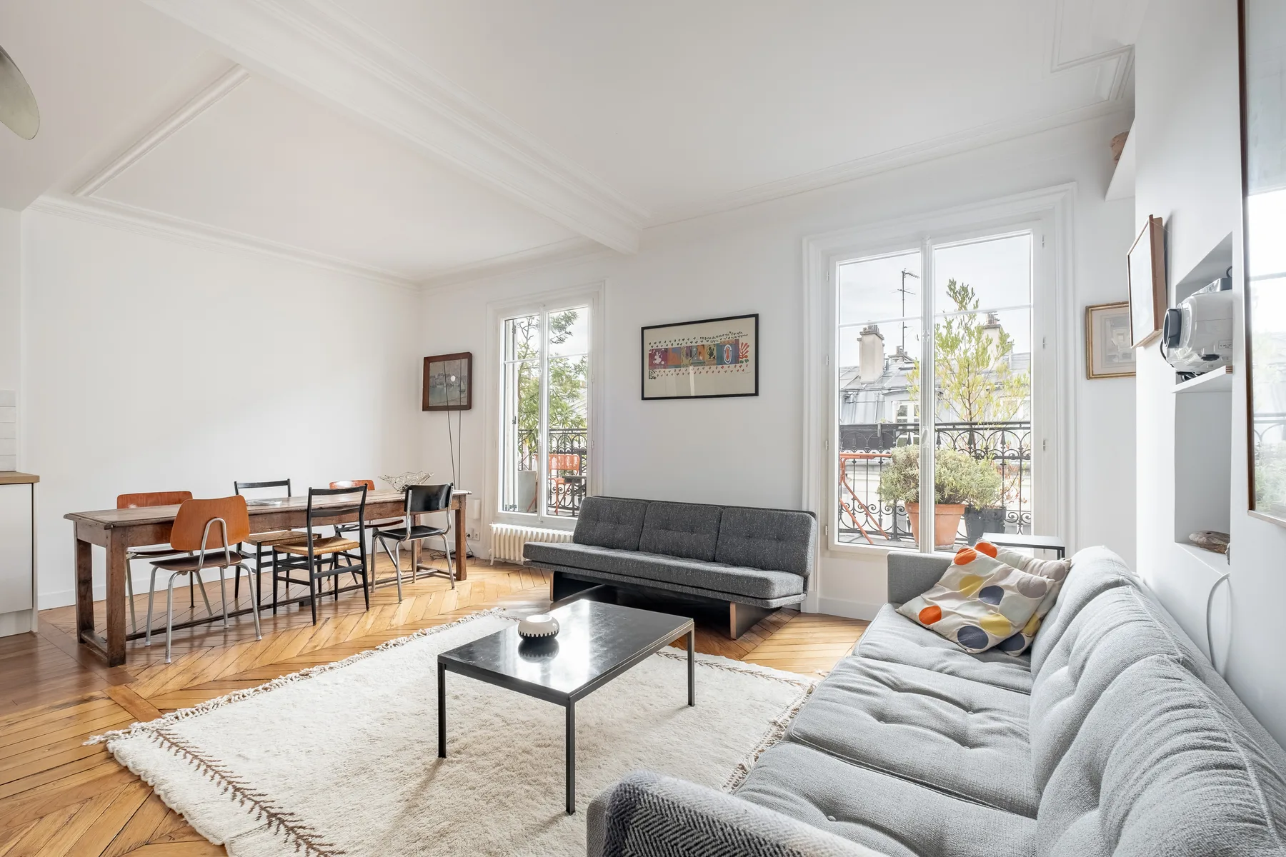 A bright living and dining room with gray seating and a dining table.