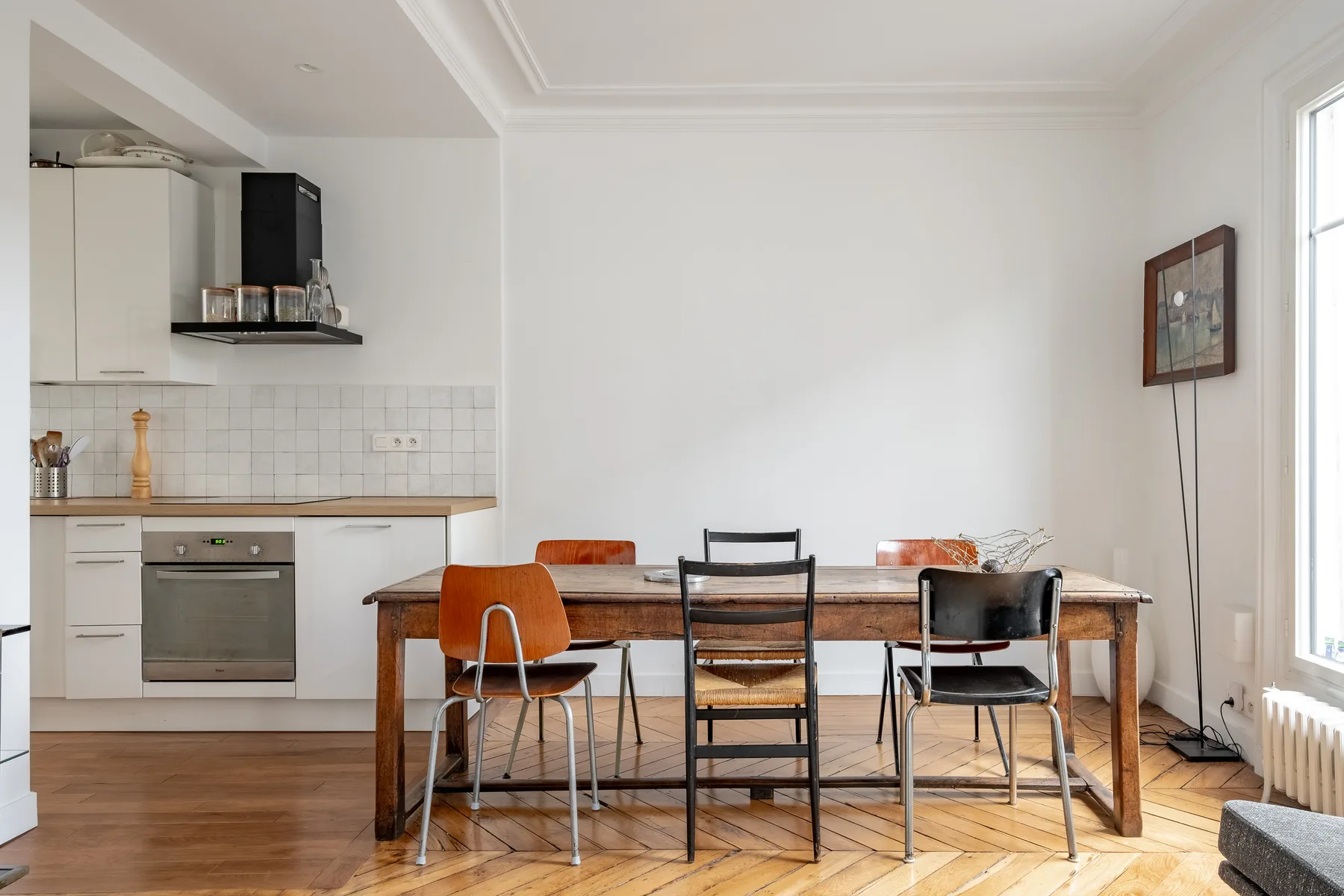 A dining area with a wooden table and chairs beside a compact kitchen.