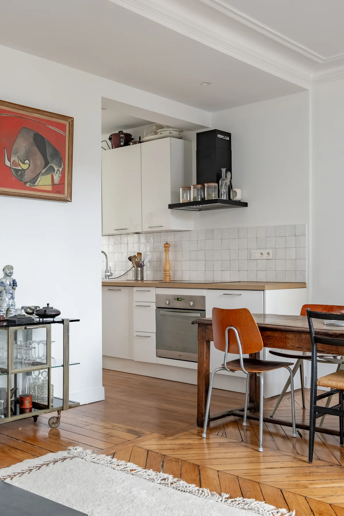 A kitchen and dining area with white cabinets, a tiled backsplash, and a wooden table.
